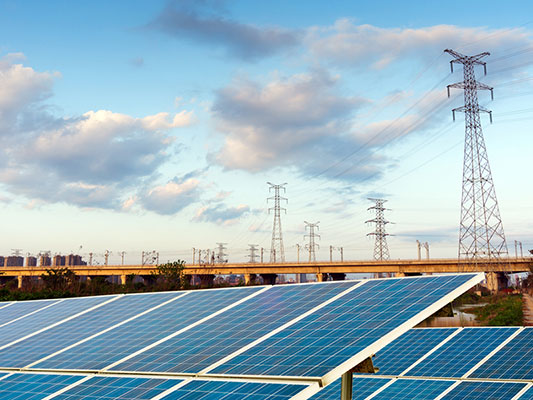 What is a solar feed-in tariff? power pole infrastructure behind ground mounted solar panels