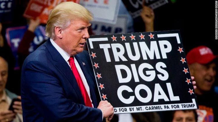 president donald trump holding up a sign at a campaign rally