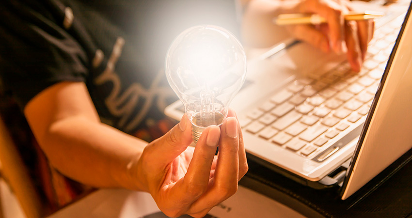 Person sitting at desk holding a light bulb