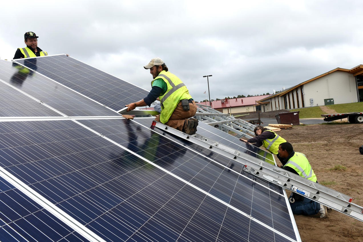 Solar installers working on a ground-mounted community solar panel installation